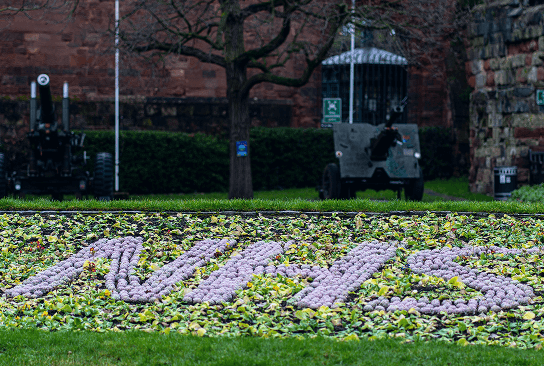 NHS letters formed by purple flowers in a garden bed